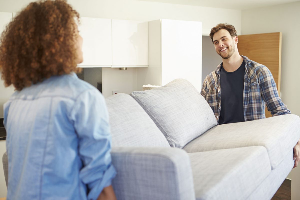 Couple Carrying Sofa As They Move Into New Home